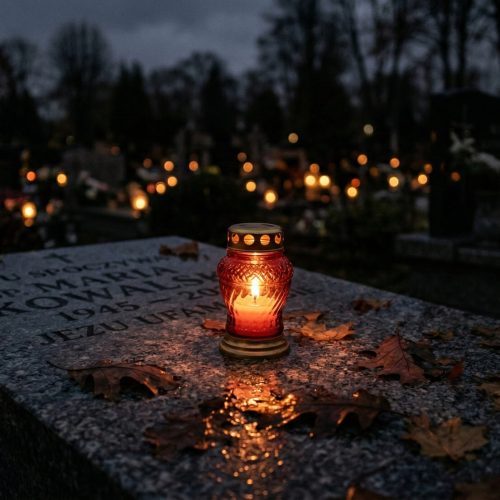 Zapalony znicz na grobie – symboliczny gest pamięci o zmarłej osobie w czasie żałoby